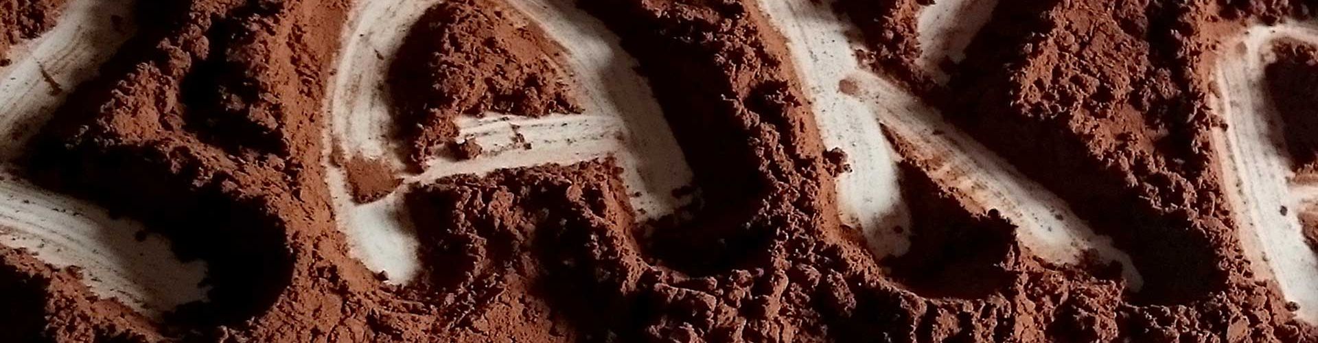 Das Wort "Kakao" mit einem Finger in Kakaopulver geschrieben